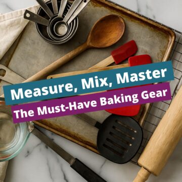 Overhead view of well-used baking tools including red silicone spatulas, wooden spoon, rolling pin, measuring cups, and glass measuring jug on a baking tray and cooling rack